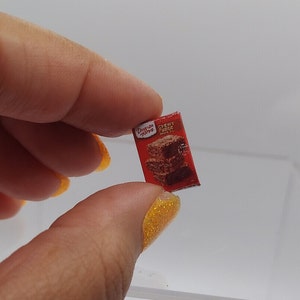 May include: A miniature box of Duncan Hines Chewy Fudge Brownie mix. The box is red with white text and a picture of a stack of brownies.