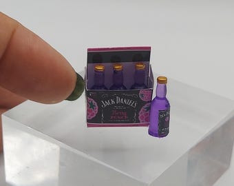 May include: A miniature six-pack of Jack Daniel's Berry Punch, with a single bottle in front. The bottles are purple with gold caps and the box is black with pink and white graphics.
