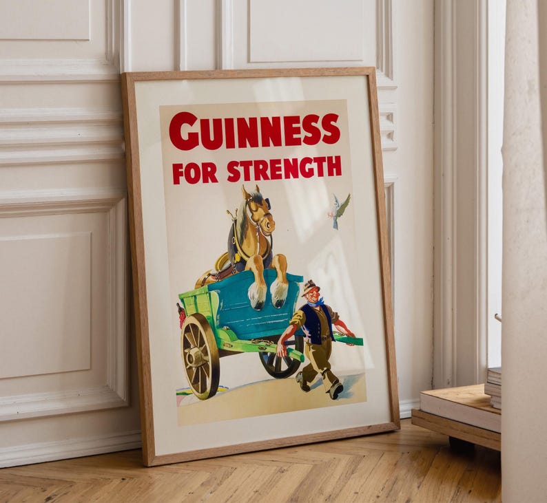 K&ouml;nnte beinhalten: Gerahmtes Vintage-Guinness-Werbeplakat. Das Poster zeigt einen Pferdewagen mit einem Mann, der daneben herl&auml;uft. Der Text "GUINNESS FOR STRENGTH" ist rot. Das Kunstwerk hat einen Vintage-Illustrationsstil.