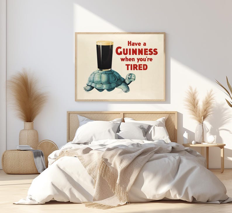 K&ouml;nnte beinhalten: Gerahmter Druck mit einem Cartoon-Schildkr&ouml;te, die ein Guinness-Bier tr&auml;gt. Der Text lautet: &bdquo;Have a Guinness when you're TIRED&ldquo; in Rot und Schwarz. Das Kunstwerk hat eine Vintage-&Auml;sthetik im Pub-Stil.