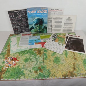 May include: A vintage board game called "Flight Leader: A Game of Air-to-Air Combat, 1939-1945". The game includes a large map, counters, and rule books. The box art features a pilot in a cockpit.