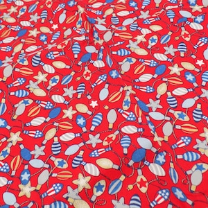 May include: A red fabric featuring a repeating pattern of light bulbs and stars. The light bulbs are colored in blue, white, and red, with some displaying stripes or star motifs. The stars are light gray or gold, scattered among the bulbs.