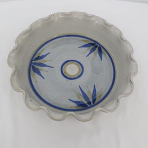 May include: A white ceramic pie dish with a blue and brown floral design. The dish has a scalloped edge.