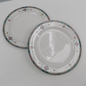 May include: A white ceramic mug with a black handle and the text "But First, Coffee" in a bold, black font. The mug is set against a blurred background, suggesting a cozy setting.