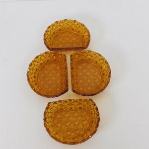 May include: Set of four amber glass dishes with a diamond pattern. The dishes are shaped like half circles and have a scalloped edge.