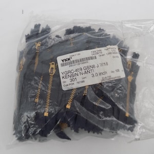 May include: A clear plastic bag filled with black zippers with gold-colored teeth and pulls. The label reads "YGRC-459 GSN8 J 7/16 KENSIN N-ANTI!" and "3.0 inch". The bag contains 100 zippers.