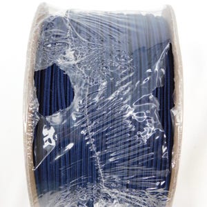 May include: A roll of navy blue cord wrapped in clear plastic. The cord appears to be tightly wound and is visible through the torn plastic. The cardboard roll is partially visible on the sides.