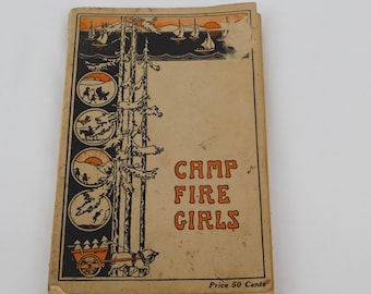 Op de afbeelding: Een vintage boekomslag met een beige achtergrond en zwarte en oranje illustraties. De titel is "Camp Fire Girls" met de prijs vermeld als "Price 50 Cents".