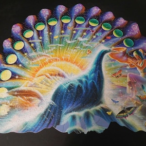 以下が含まれることがあります： 鮮やかな尾を持つ孔雀を描いたカラフルなジグソーパズル。太陽、蝶、天体の要素が特徴です。パズルのデザインは、青、紫、黄、オレンジの色合いを取り入れ、気まぐれで芸術的なシーンを作り出しています。