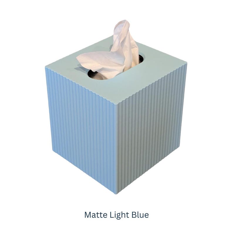 May include: A light blue tissue box with a ribbed texture. The box has a square shape and a white tissue is partially visible.