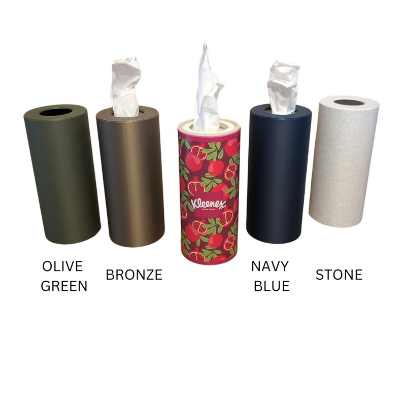 May include: Five tissue box holders in different colours: olive green, bronze, red with a pomegranate pattern, navy blue, and stone. The tissue box holders are all cylindrical and have a simple design.