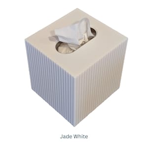 May include: A white square tissue box cover with a ribbed texture. The cover has a slot for tissues and a small opening for pulling out tissues. The text "Jade White" is printed below the box.