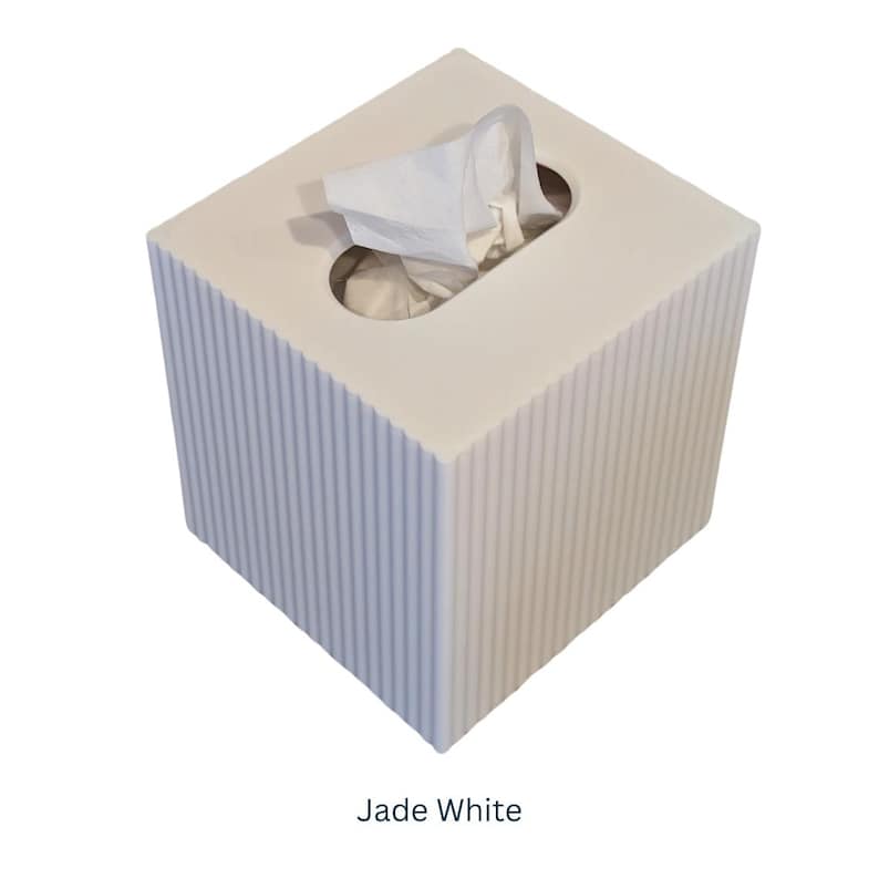 May include: A white square tissue box cover with a ribbed texture. The cover has a slot for tissues and a small opening for pulling out tissues. The text "Jade White" is printed below the box.