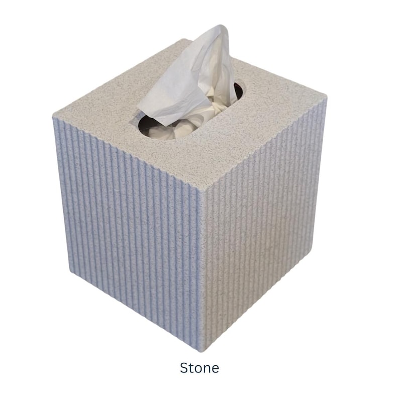 May include: A gray stone tissue box cover with a textured surface. The tissue box cover has a rectangular shape and a slot for tissues.