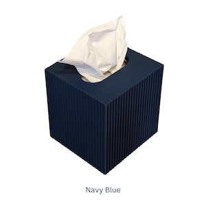 May include: A navy blue tissue box cover with a ribbed texture. The cover is square and has a slot for tissues.