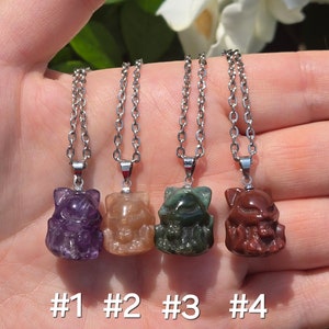 May include: Four silver necklaces with different colored stone charms in the shape of a cat. The charms are purple, brown, green, and red. The necklaces are labeled #1, #2, #3, and #4.