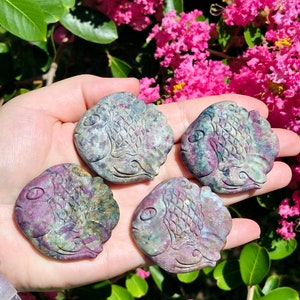 May include: Four carved gemstone fish, each with a unique pattern of pink, green, and gray. The fish are made of a polished stone with a smooth, shiny surface.