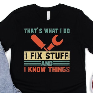 May include: Black t-shirt with a vintage-style graphic that says "That's what I do I fix stuff and I know things". The graphic features a screwdriver and wrench in a retro color scheme.