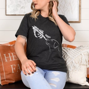May include: A dark grey t-shirt with a white skeleton hand pointing at a dog with the text "BOOP!" printed on the front.