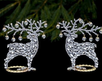 May include: Two silver reindeer ornaments with crystal accents and gold-coloured branches with clear glass ornaments hanging from them.