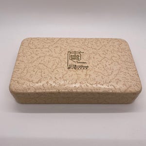 May include: A rectangular, beige box with a speckled pattern. The box features the text "BOND BOYD ORIGINAL" in black, with an illustration of a horse-drawn carriage. The box has a glossy finish.