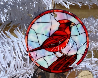 May include: Hand-crafted ceramic ornament, approximately 3 inches in diameter, featuring a vibrant red cardinal bird design. The ornament has a stained-glass effect with a gold hanging cord. The text "Photograph of completed ornament" is at the bottom.