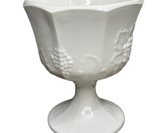 May include: White, vintage-style goblet with a hexagonal bowl and a pedestal base. The goblet features a grape and leaf design on the sides. The stem is smooth and the bowl is wide, perfect for serving beverages.