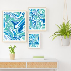Pu&ograve; includere: Tre stampe d'arte astratta incorniciate con motivi a spirale blu, verdi e bianchi. Le stampe sono appese a una parete bianca sopra un tavolo di legno con una pianta in vaso.