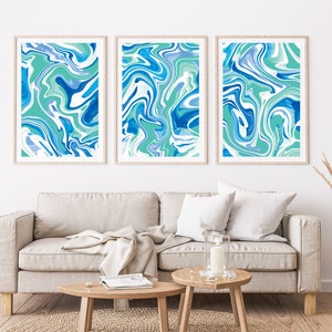 Pu&ograve; includere: Tre stampe d'arte astratta incorniciate con un designo marmoreo blu e verde. Le stampe sono appese a un muro bianco sopra un divano grigio chiaro.