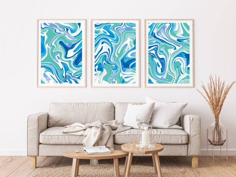 Pu&ograve; includere: Tre stampe d'arte astratta incorniciate con un designo marmoreo blu e verde. Le stampe sono appese a un muro bianco sopra un divano grigio chiaro.