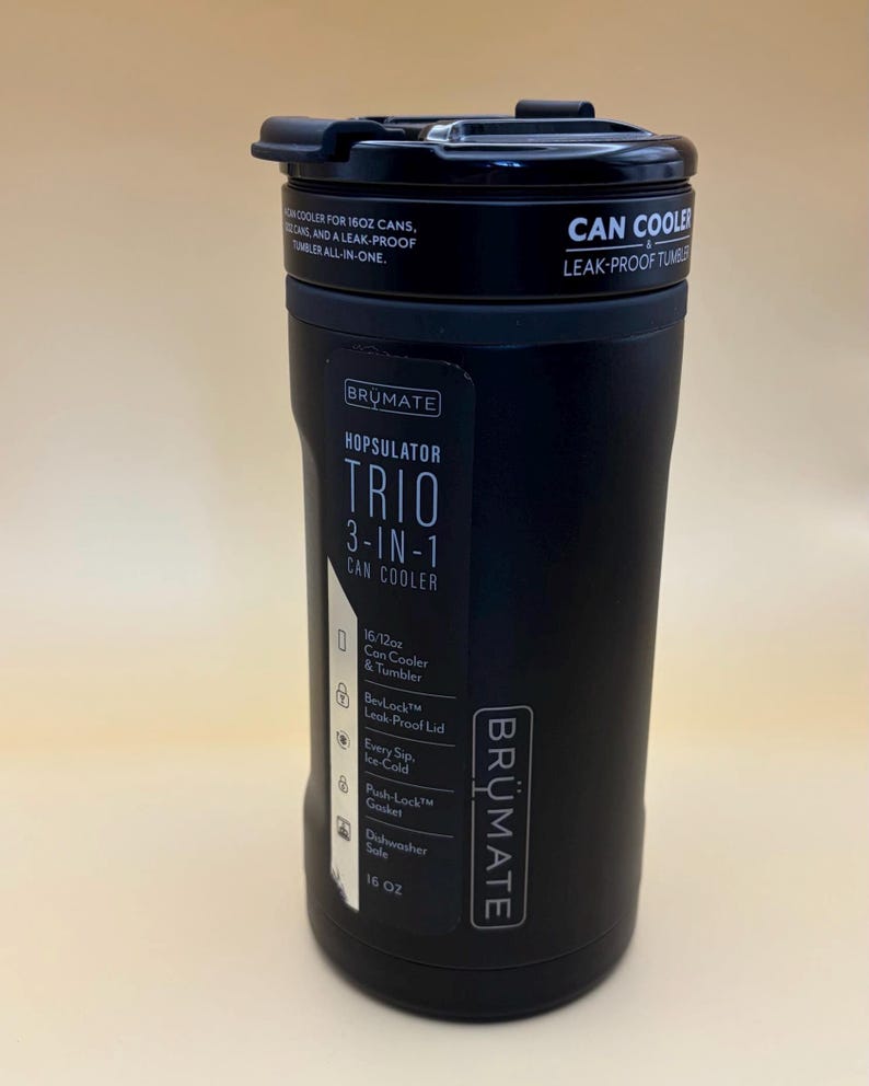 Op de afbeelding: Zwarte BRUMATE Hopsulator Trio 3-in-1 blikjeskoeler en tumbler. Voorzien van een lekvrij deksel, een Push-Lock pakking en een vaatwasmachinebestendig ontwerp. Geschikt voor 473 ml blikjes. De tekst luidt "CAN COOLER LEAK-PROOF TUMBLER ALL-IN-ONE."