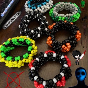 May include: A collection of colorful kandi bracelets, featuring black and white, green and yellow, orange and black, red and black, and blue and white color combinations. The bracelets are made of small plastic beads and are arranged in a spiral pattern. The word "Creepypasta" is written on a black surface in the background.
