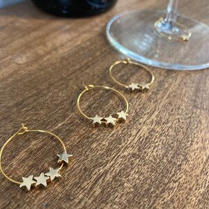 Könnte beinhalten: Drei goldene Creolen mit jeweils fünf goldenen Sternanhängern.