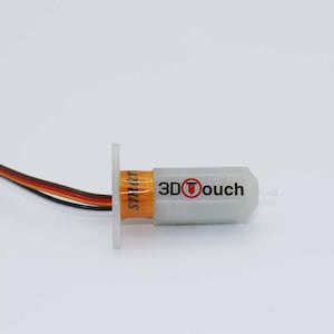 May include: A 3D Touch auto bed leveling sensor for 3D printers. The sensor is white with an orange band and the text "3D Touch" in black. It has a small white mounting plate and multi-colored wires.