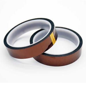Könnte beinhalten: Zwei Rollen braunes Thermoband mit schwarzem Rand und weißem Innenraum sind auf weißem Hintergrund gestapelt. Das Band hat einen gelben Streifen mit dem Aufdruck "Kapco". Das Band wird für Wärmeübertragungsanwendungen verwendet.