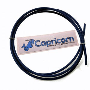 May include: A coil of dark blue Capricorn PTFE Bowden tubing, secured with a metal ring. A white label with the Capricorn logo and text is visible.