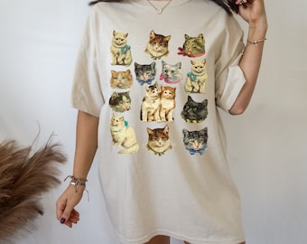 May include: A beige oversized t-shirt with a vintage print of various cats wearing bows and collars. The cats are in a grid pattern on the front of the shirt.