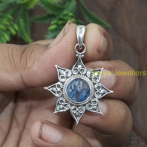 May include: A silver pendant featuring a blue gemstone set within a star-shaped design. The pendant is suspended from a silver chain.