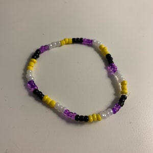 May include: A beaded bracelet with alternating purple, white, yellow, and black beads.