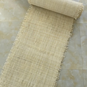 Pode incluir: Um rolo de tecido natural bege, tecido, franjado, com um padr&atilde;o de grade.