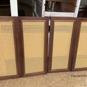 May include: Four rectangular cabinet doors with dark brown wooden frames and woven cane inserts. The cane has a light tan color and a grid-like pattern. The doors are arranged side by side, suggesting they are part of a larger piece of furniture.