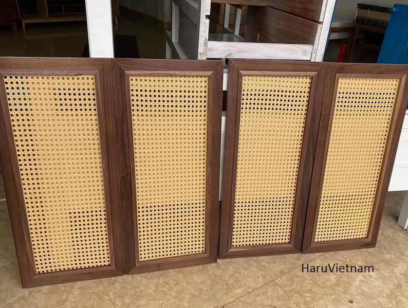 May include: Four rectangular cabinet doors with dark brown wooden frames and woven cane inserts. The cane has a light tan color and a grid-like pattern. The doors are arranged side by side, suggesting they are part of a larger piece of furniture.