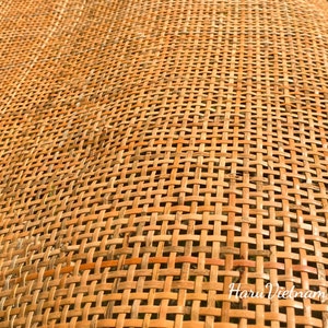 May include: Close-up of a woven rattan surface in a natural brown colour. The weave is a tight, even pattern, creating a smooth, textured surface.