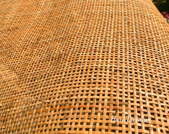 Puede incluir: Primer plano de una superficie de ratán tejido de color marrón natural. El tejido es apretado y uniforme, creando una superficie lisa y texturizada.