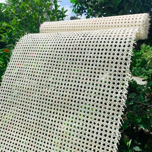 K&ouml;nnte beinhalten: Wei&szlig;es Rohrgeflecht, ein gewebtes Material, das f&uuml;r Stuhlsitze und -lehnen verwendet wird, ist aufgerollt und im Freien ausgestellt. Das Geflecht besteht aus nat&uuml;rlichen Materialien und hat ein traditionelles Aussehen.