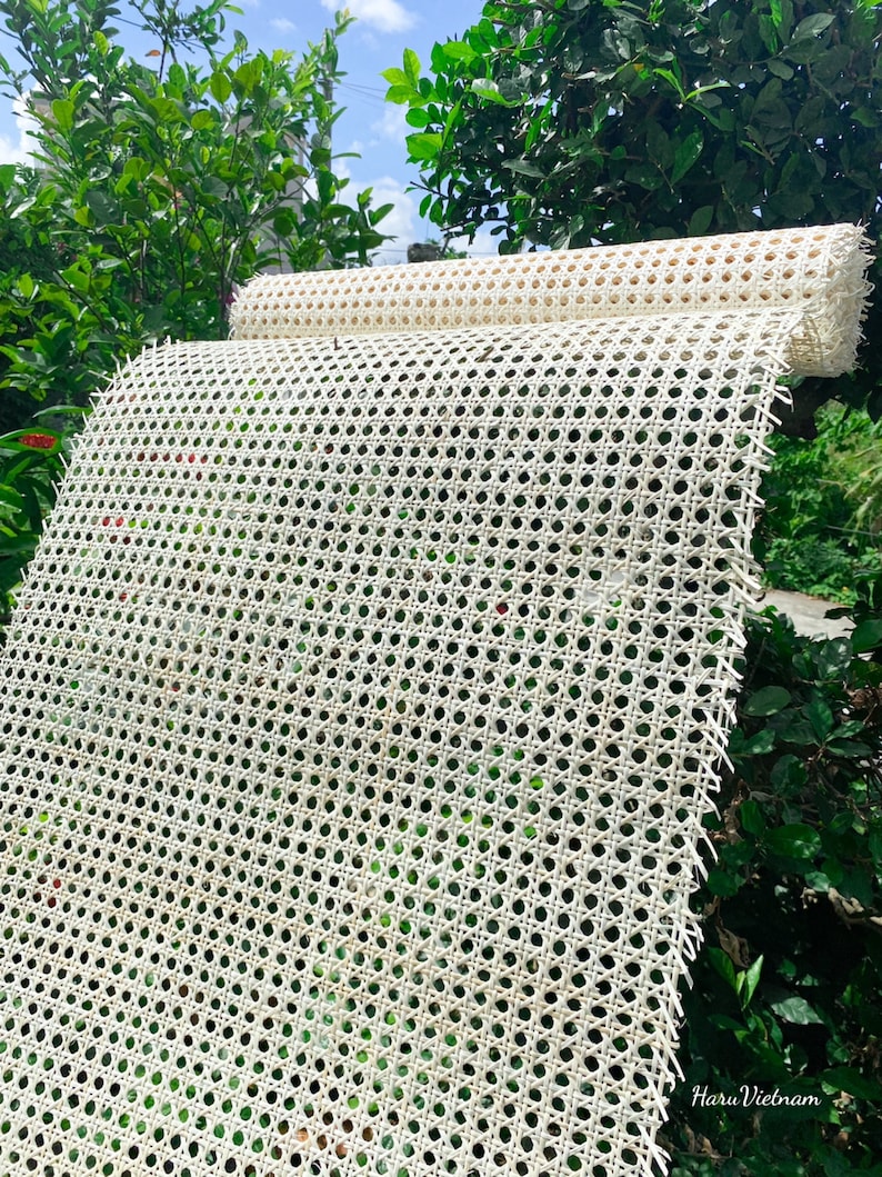 K&ouml;nnte beinhalten: Wei&szlig;es Rohrgeflecht, ein gewebtes Material, das f&uuml;r Stuhlsitze und -lehnen verwendet wird, ist aufgerollt und im Freien ausgestellt. Das Geflecht besteht aus nat&uuml;rlichen Materialien und hat ein traditionelles Aussehen.