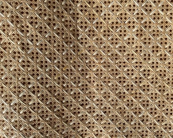 Könnte beinhalten: Nahaufnahme eines geflochtenen Cane- oder Rattanmaterials, das oft für Stuhlsitze oder Möbel verwendet wird. Das Material ist hellbraun und hat ein Rautenmuster.