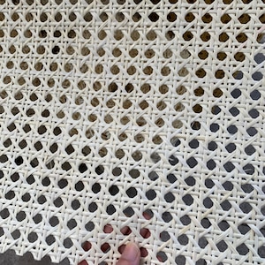 K&ouml;nnte beinhalten: Wei&szlig;es Rohrgeflecht, ein gewebtes Material, das f&uuml;r Stuhlsitze und -lehnen verwendet wird, mit einer Nahaufnahme des komplizierten Flechtmusters.