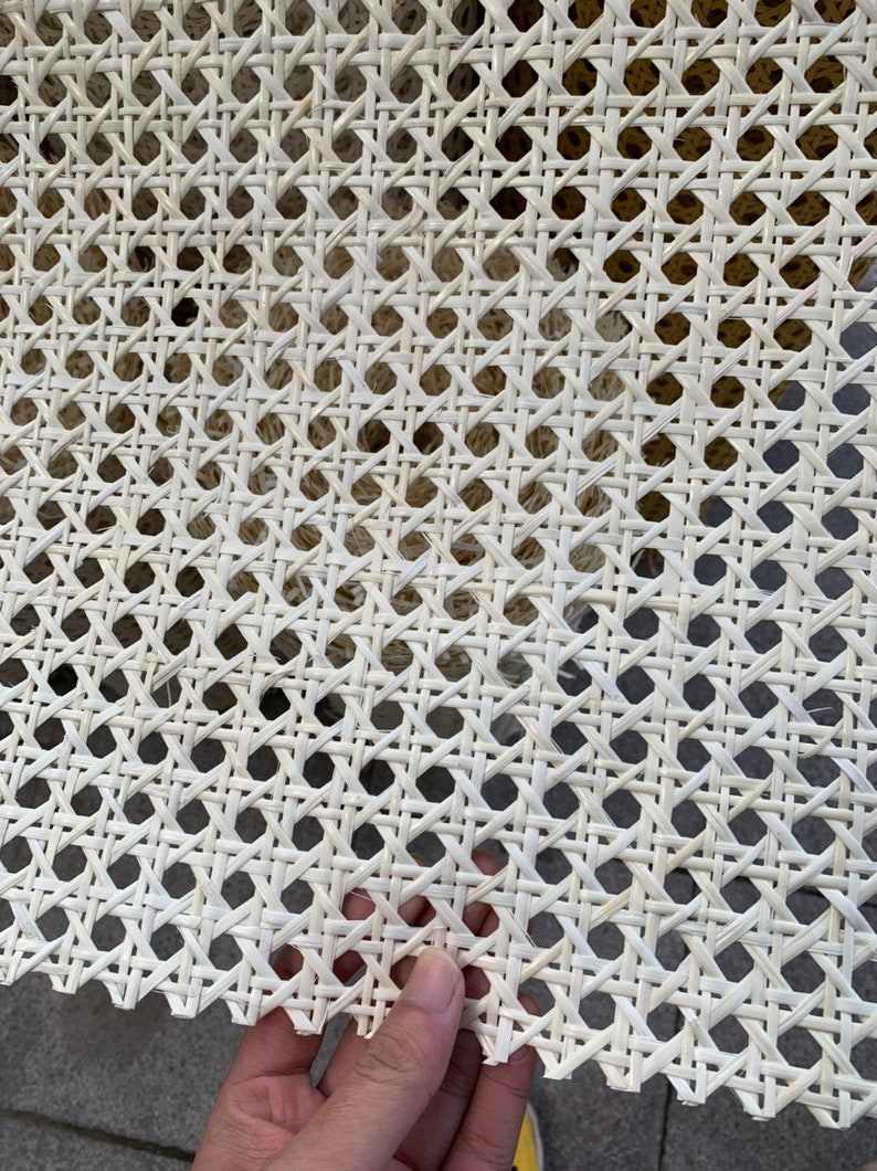 K&ouml;nnte beinhalten: Wei&szlig;es Rohrgeflecht, ein gewebtes Material, das f&uuml;r Stuhlsitze und -lehnen verwendet wird, mit einer Nahaufnahme des komplizierten Flechtmusters.