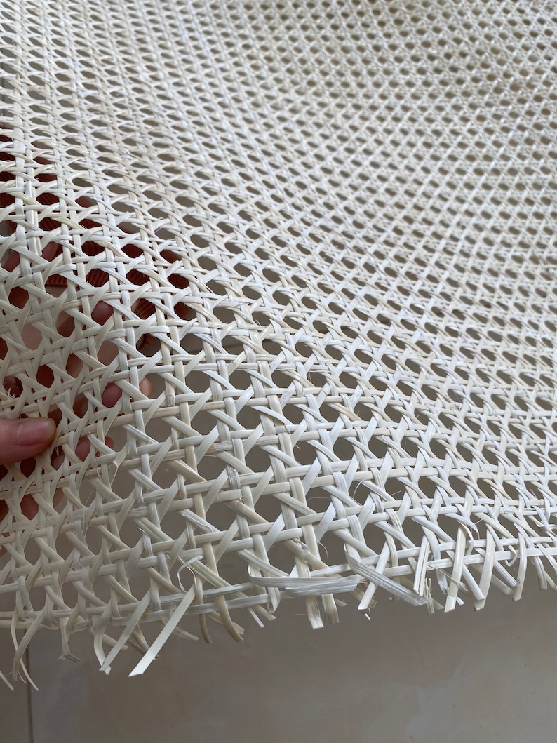 K&ouml;nnte beinhalten: Wei&szlig;es Rohrgeflecht, ein gewebtes Material, das f&uuml;r Stuhlsitze und -lehnen verwendet wird, mit einer Nahaufnahme des komplizierten Flechtmusters.